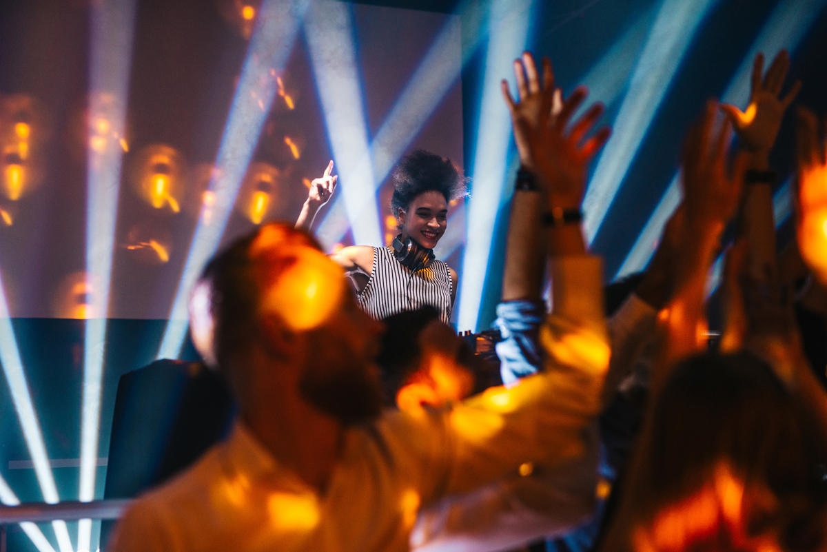 Shot of a female DJ playing music in the club. (c) AdobeStock