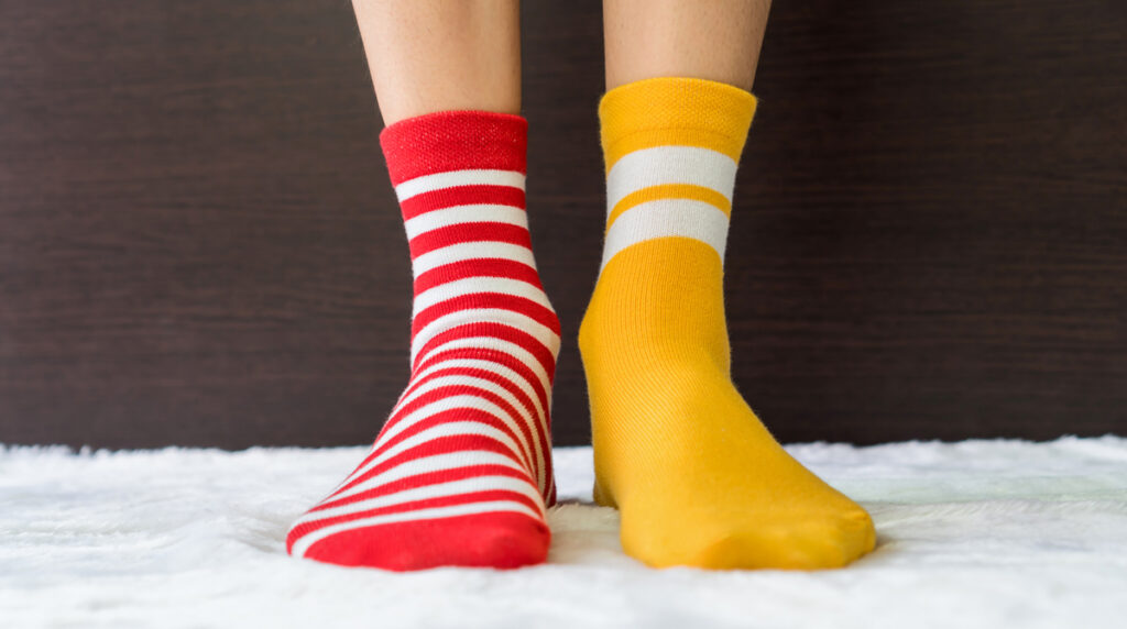 Legs in socks two colors alternate, Red and yellow side stand on white fabric floor, Stichwort Socken.
(c) AdobeStock