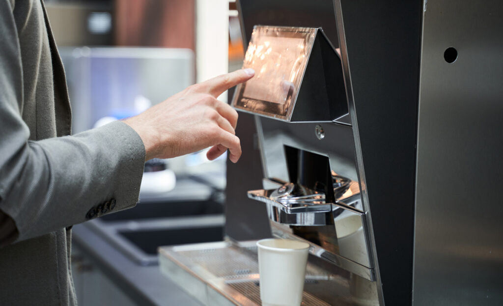 Male hand pressing button of machine for coffee while resting in the modern kitchen after long negotiations with business partners, keyword Überstunden.
(c) AdobeStock