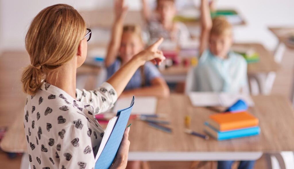 Eine Lehrerin in einer Klasse zeigt auf ein aufzeigendes Kind, Stichwort Bildungsbudget.
(c) AdobeStock