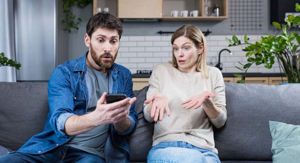 Ein Mann mit einem Smartphone und eine Frau auf einer Couch beim heftigen Diskutieren, Stichwort was sollen wir essen.
(c) AdobeStock