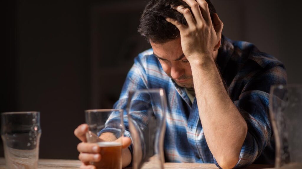 Ein betrunkener Mann mit einer Hand an einem fast leeren Glas Bier und mit der anderen seinen Kopf am Tisch abstützend, Stichwort Spermien.
(c) AdobeStock