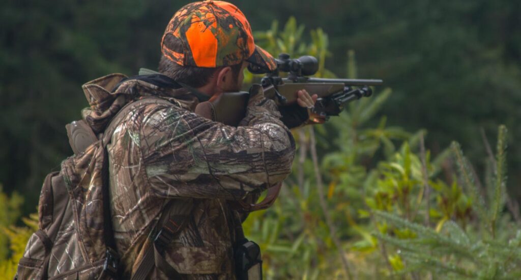 Ein Jäger mit seinem Gewehr im Anschlag, Stichwort Rasenmähen.
(c) AdobeStock