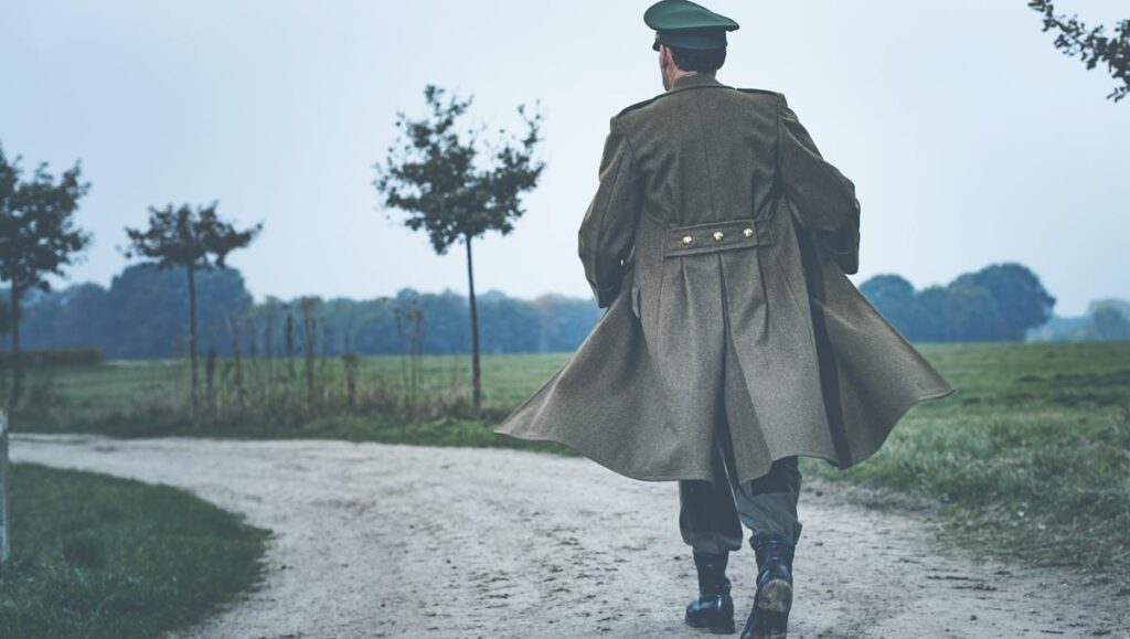 Ein Mann mit Wehrmachtsmantel und Kappe auf einem Schotterweg, Stichwort Thüringen.
(c) AdobeStock