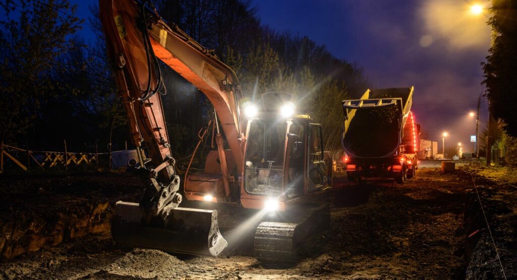 Ein Bagger und ein LKW bei der Arbeit in der Nacht, Stichwort S8.
(c) AdobeStock