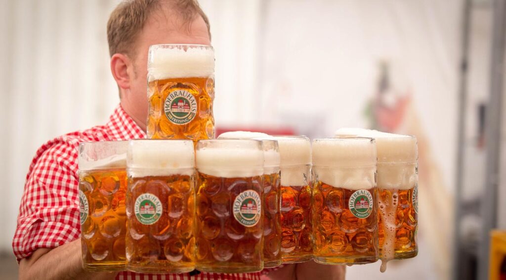 Ein Mann, der zahlreiche Maß Bier trägt, Stichwort Wiesn.
(c) Pixabay.com