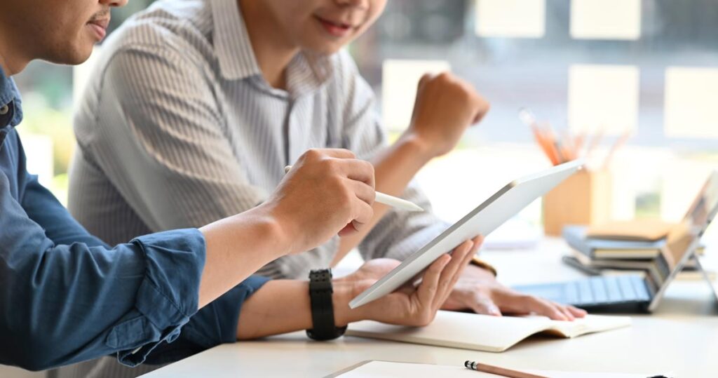 Zwei Männer an einem Schreibtisch bei einer Besprechung, Stichwort Kurz.
(c) AdobeStock