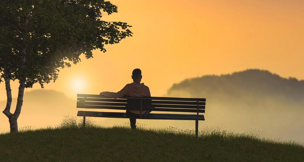 Ein Mann auf einer Bank beim Anschauen eines Sonnenuntergangs, Stichwort Verhütung.
(c) AdobeStock